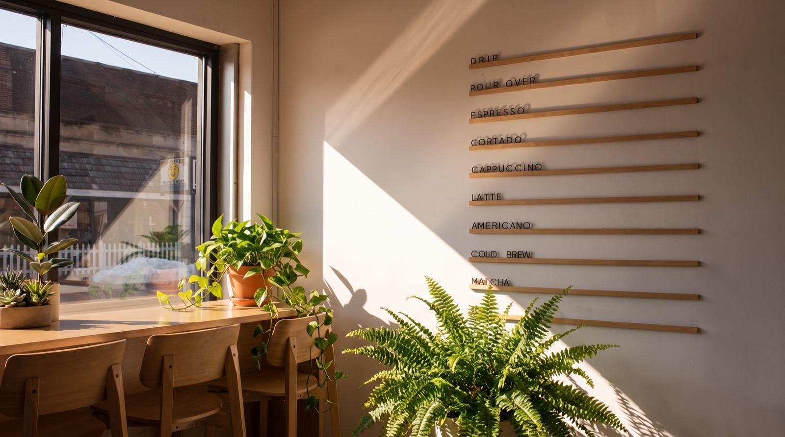 The wood-dowel drink board mounted on the exposed brick wall, framed by trailing greenery.