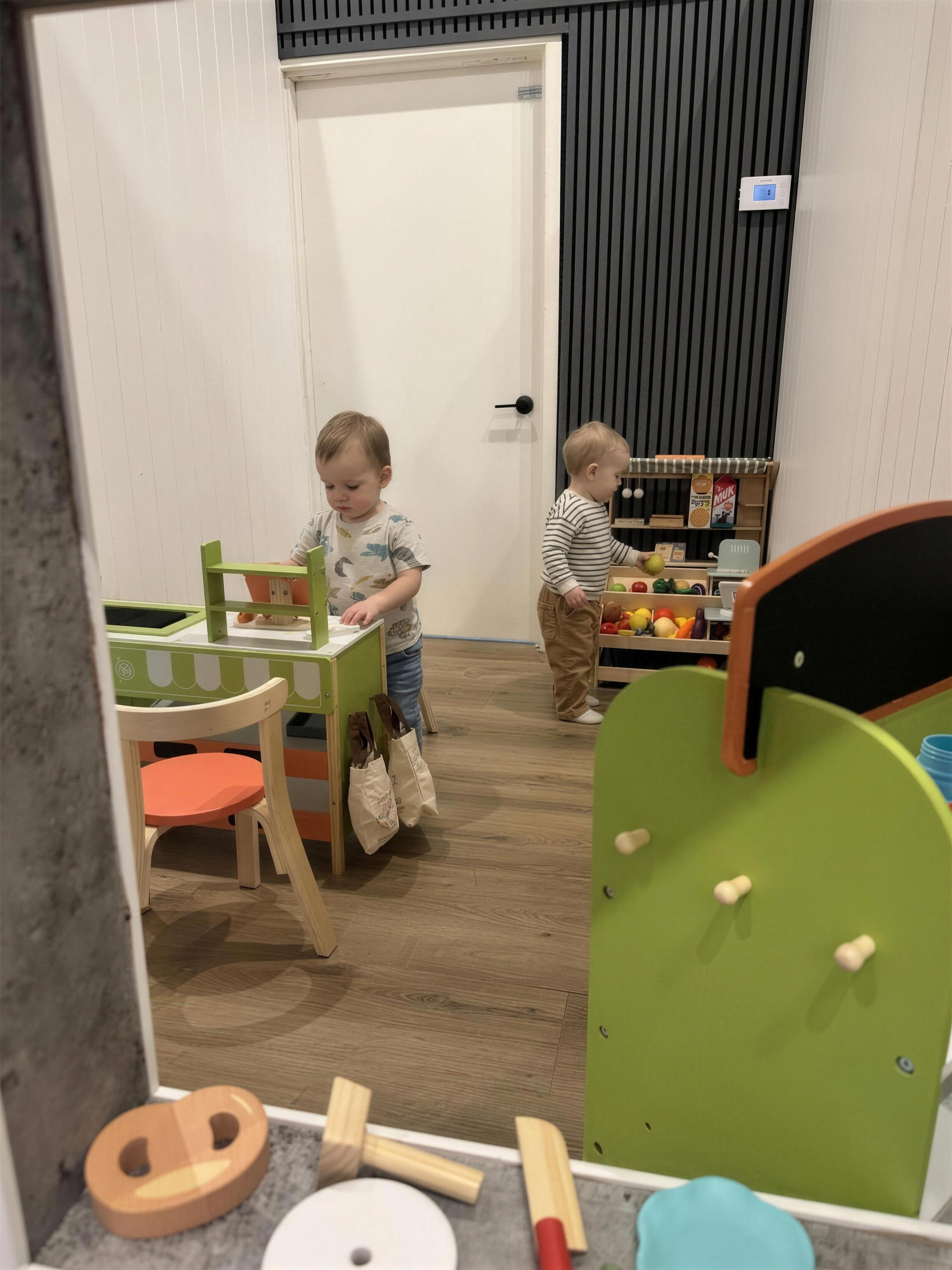 Two toddlers shopping the produce shelves at the little grocery.