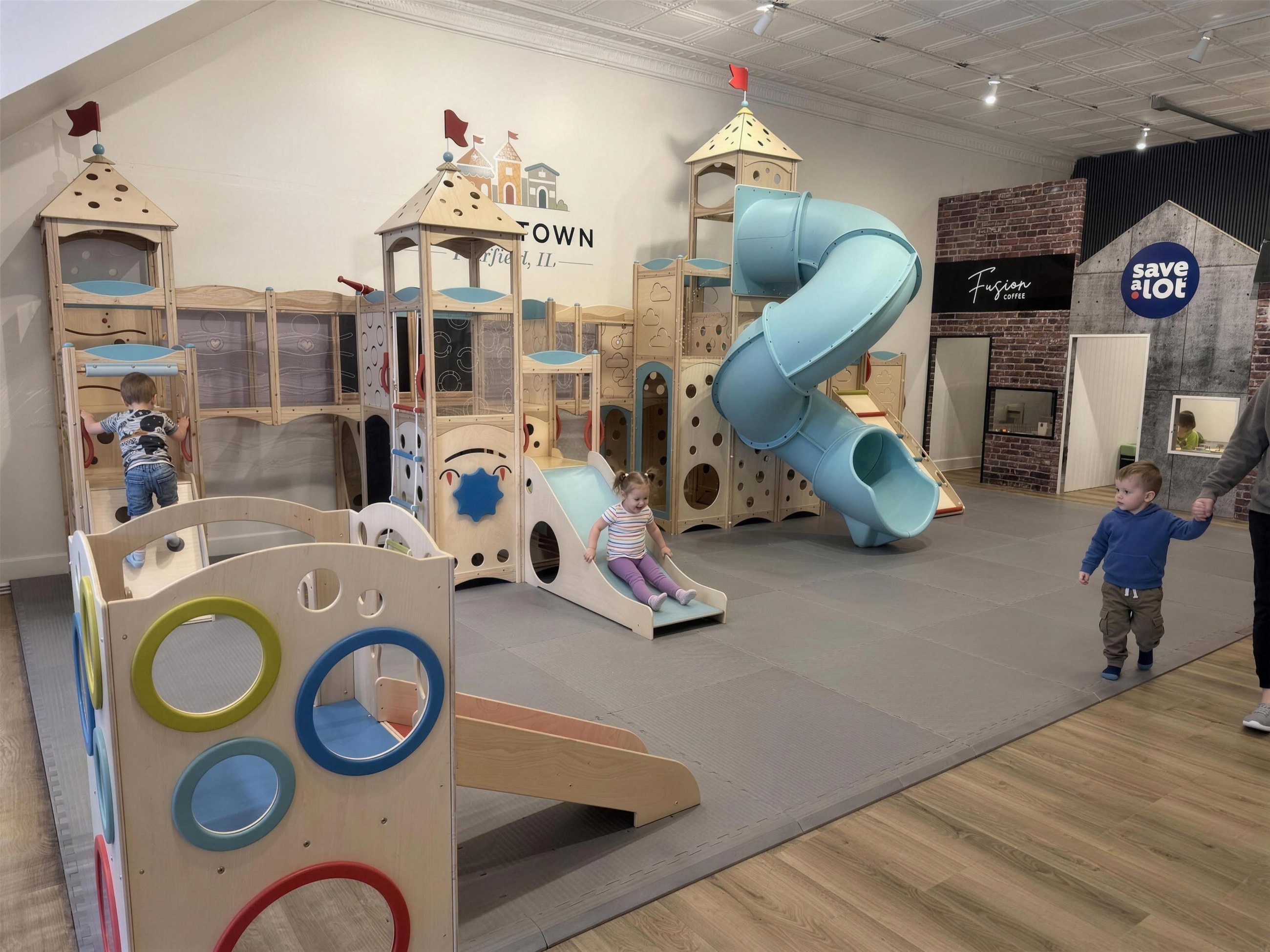 The full play floor at Little Town, with the Fusion Coffee and grocery storefronts along the back wall.